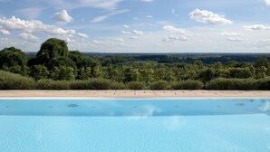 Una piscina con vistas a un bosque y un paisaje lejano.