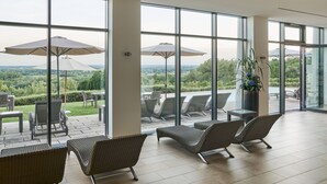 Un espacio interior amplio con ventanas grandes, sillones de mimbre y sombrillas.