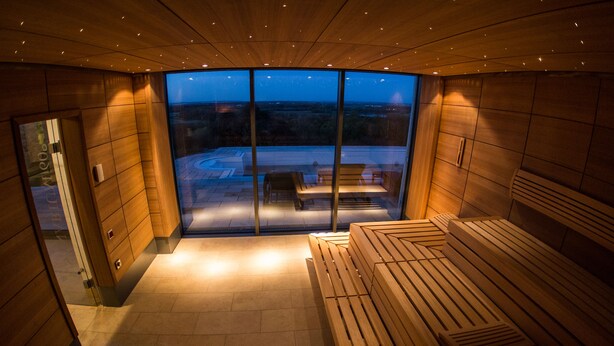 Un spa moderno con bancos de madera y una pared de vidrio que ofrece vistas al exterior.