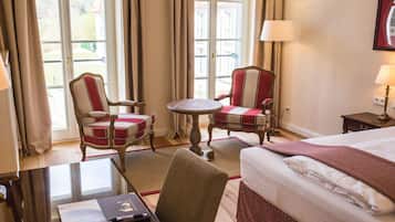 Ein Hotelzimmer mit einem Bett, zwei Sesseln, einem kleinen runden Tisch und einem Schreibtisch mit einem Laptop.