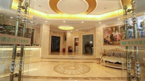 A hotel lobby with a central circular design on the floor, a reception desk, and a sofa. - Vienna Hotel (Shenzhen)