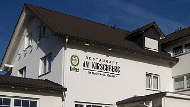 Un edificio con un letrero que dice 'RESTAURANT AM KIRSCHBERG' y 'Licher im Hotel Royal Garden'.