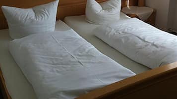Cama doble con sábanas y almohadas blancas en una habitación de hotel.