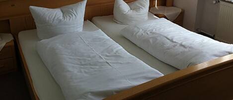Cama doble con sábanas y almohadas blancas en una habitación de hotel.
