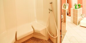 A corner of a bathroom with a shower, a toilet, and a sink.