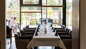 A dining area with a table set for six, large windows, and a view of the outdoors. - Trend Hotel (Banzkow)