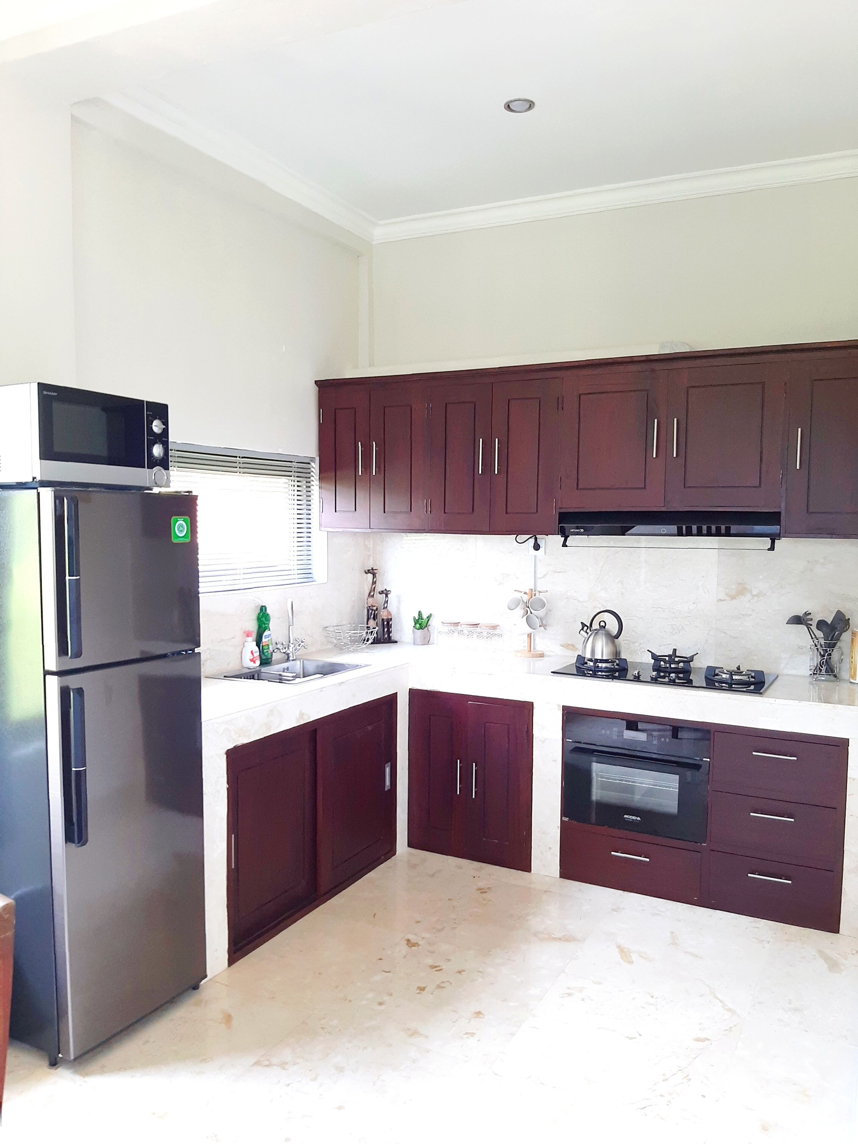 A modern kitchen with stainless steel appliances, dark wooden cabinets, and a white countertop.