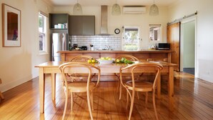 A modern kitchen with wooden flooring, a central island with chairs, pendant lighting, and a view of the outdoors. - Yarra Valley Vineyard Cottage - premier location with spectacular views. (Gruyere)