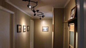 Un couloir aux murs en bois, avec un luminaire au plafond et des tableaux encadrés accrochés au mur.