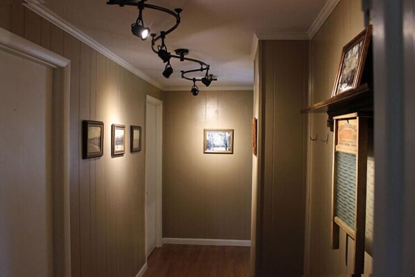Un couloir aux murs en bois, avec un luminaire au plafond et des tableaux encadrés accrochés au mur.