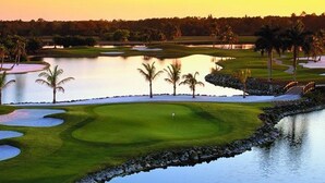 Un parcours de golf agrémenté d’obstacles d’eau, de bunkers de sable et de palmiers.