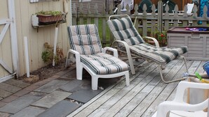 A wooden deck with two striped lounge chairs and a white plastic chair. - North Wildwood Townhouse, unit A. One Block To The Beach. Ocean Views From Deck. (North Wildwood)