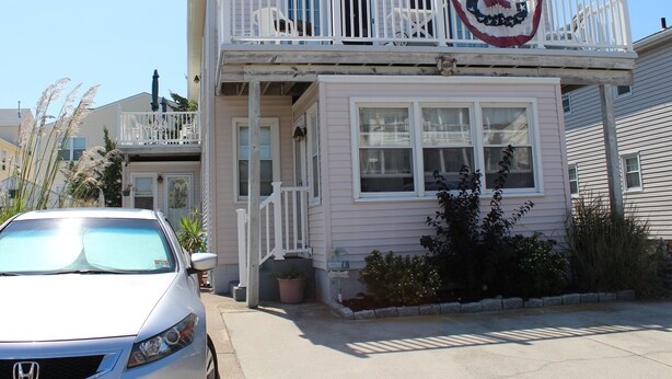 A two-story building with a balcony, a welcome sign, and a flag. - North Wildwood Townhouse, unit A. One Block To The Beach. Ocean Views From Deck. (North Wildwood)