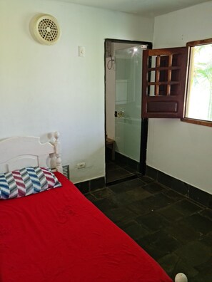 Ein Schlafzimmer mit Bett, Fenster mit Blick, Tür und Deckenventilator.