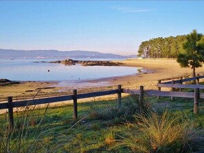 Enjoy a serene beach setting with a clear view of the ocean and surrounding hills.