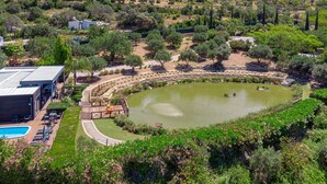 A landscaped area with a swimming pool, a circular pond, and a wooden deck. - Stunning 3 bedroom en-suite house in farm with pool (Estoi)
