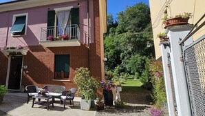 Un bâtiment à deux étages doté d’un balcon, d’une porte et d’un petit patio aménagé avec du mobilier d’extérieur.