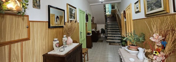 A hallway with wooden paneling, a staircase, and various decorative items including vases and plants. - Mini Accommodations Cavanna  (Alessandria)