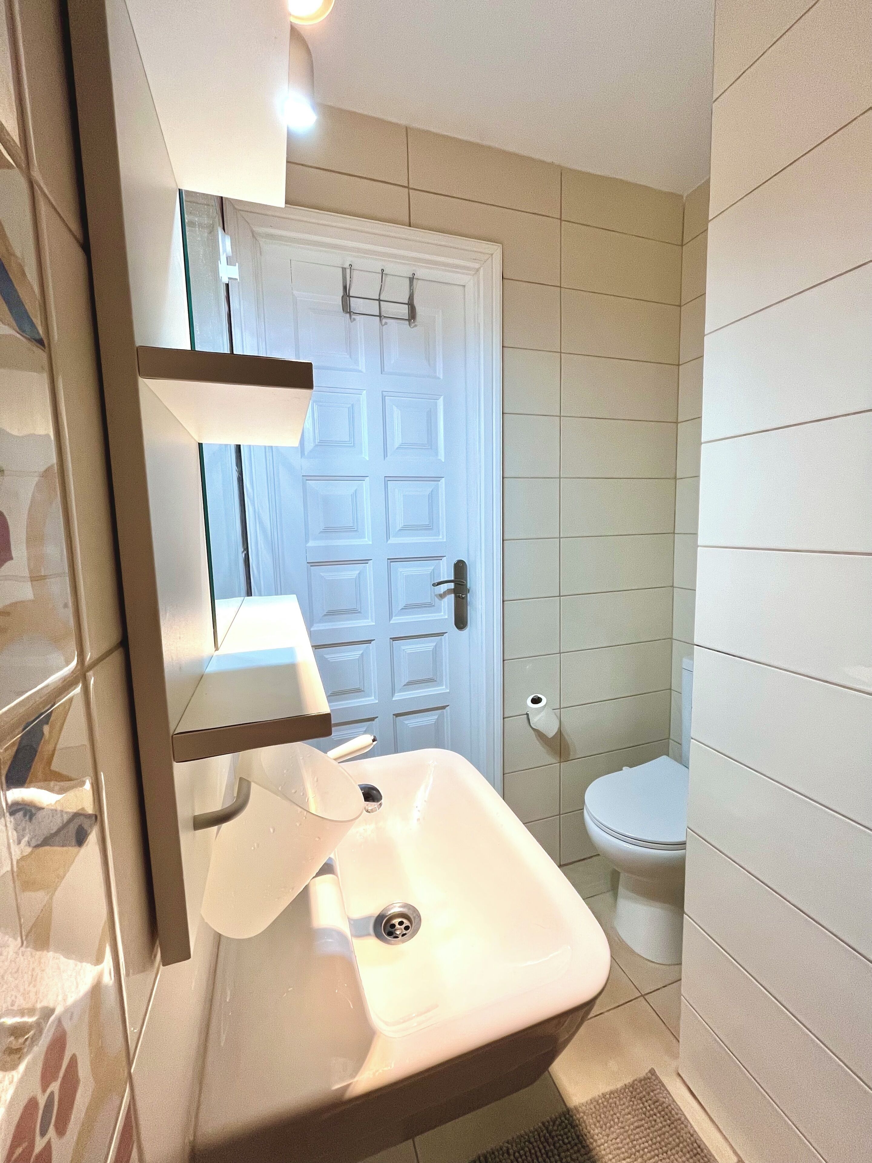 Un bagno con un lavandino bianco, un water e una porta con maniglia.