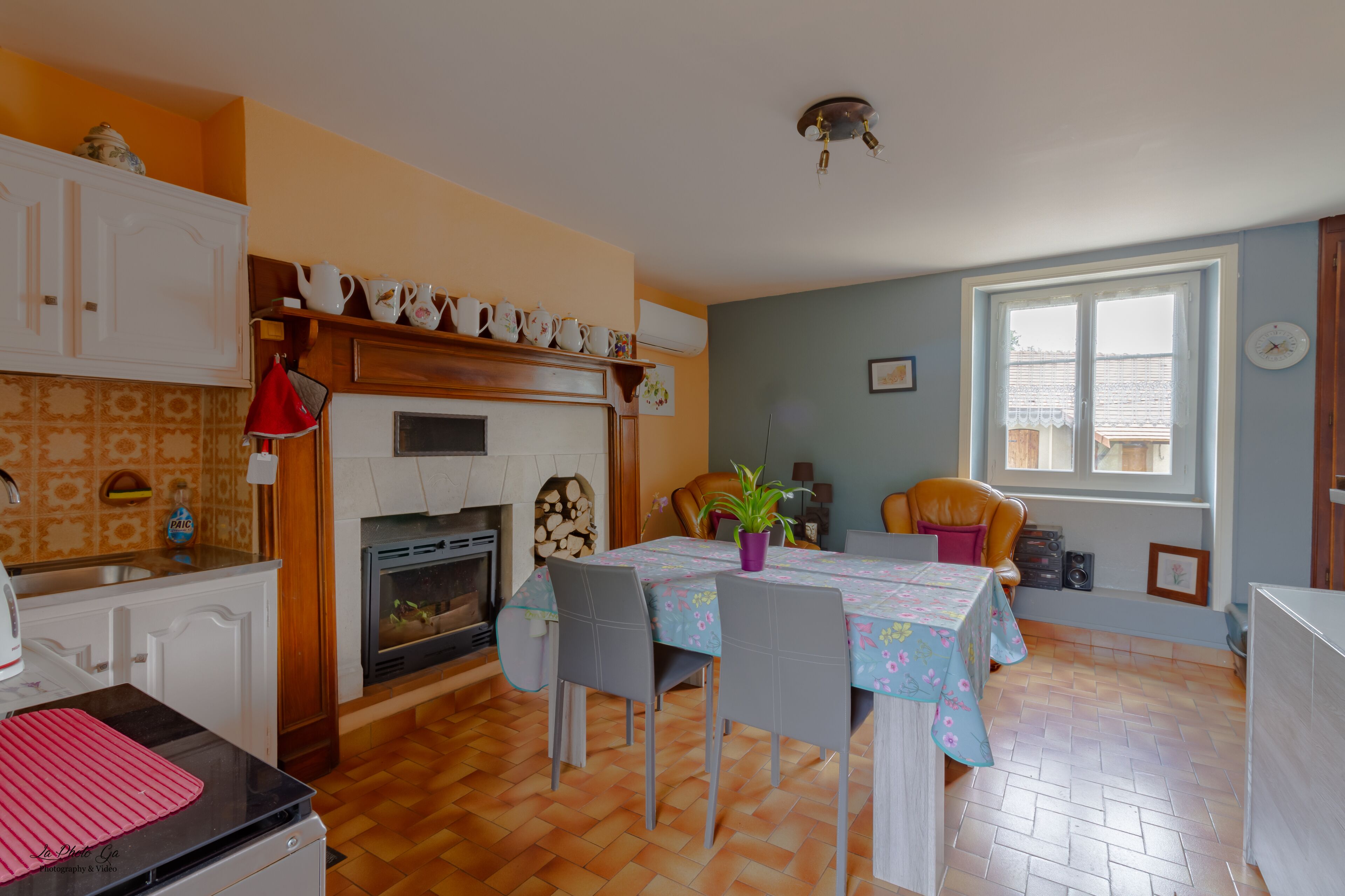 Un comedor con mesa dispuesta para cuatro, chimenea y ventana con persianas.