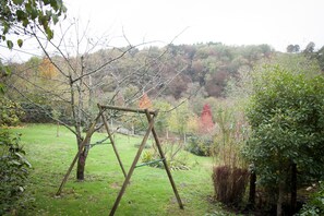 A wooden swing set in a grassy garden with trees and shrubs in the background. - Jumilhac le grand- House of character with garden (Jumilhac-Le-Grand)