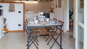 A kitchen with a wooden ceiling, white cabinets, and a dining table with chairs. - bcube - bed and breakfast in the village (Pavia)