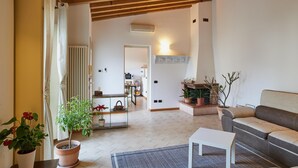 A spacious living area with a wooden ceiling, a sofa, a coffee table, and potted plants. - bcube - bed and breakfast in the village (Pavia)