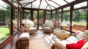 A sunroom with large windows, wicker furniture, and a ceiling fan. - Beautiful detatched cottage situated within a small hamlet near Bamburgh. (waren mill)