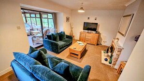A living room with a sofa set, a coffee table, a TV, and a fireplace. - Beautiful detatched cottage situated within a small hamlet near Bamburgh. (waren mill)