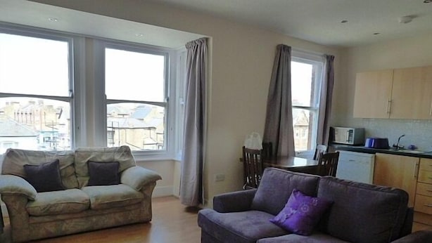 A living room with two sofas, a dining table, and a kitchen area with cabinets and appliances. - Lovely Light, Spacious Flat With Sea View (Herne Bay)