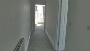 A narrow hallway with a white door on the right, a vent on the left, and a carpeted floor. - Lovely Light, Spacious Flat With Sea View (Herne Bay)
