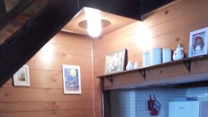 Een gezellig hoekje met een houten bankje, een tafel met een witte tafelkleed en een klein rekje met keukengerei.