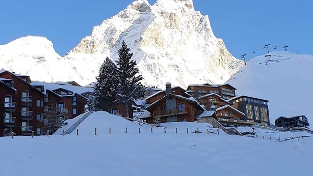 Een met sneeuw bedekte berg met een wintersportgebied op de voorgrond.