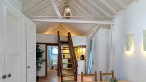 A kitchen with a wooden staircase, a dining table with chairs, and a potted plant on the table.