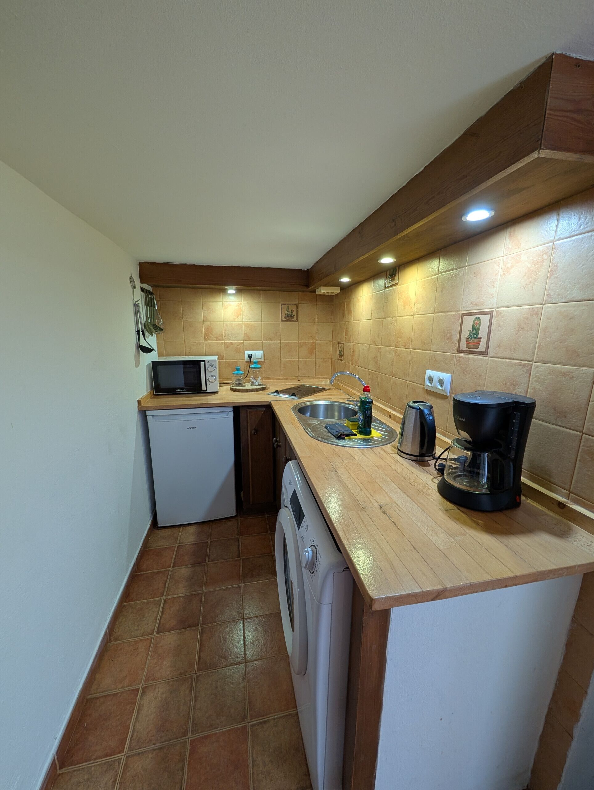 Cozinha compacta com micro-ondas, cafeteira e pia.
