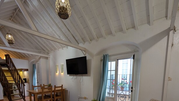 A spacious living area with a wooden table, sofa, and TV.
