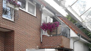 A two-story brick building with a white door and a black car parked in front.