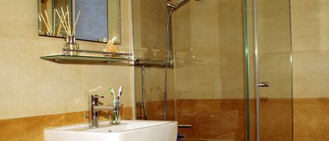 A bathroom with a glass-enclosed shower, a white sink with a mirror above it, and a toilet.