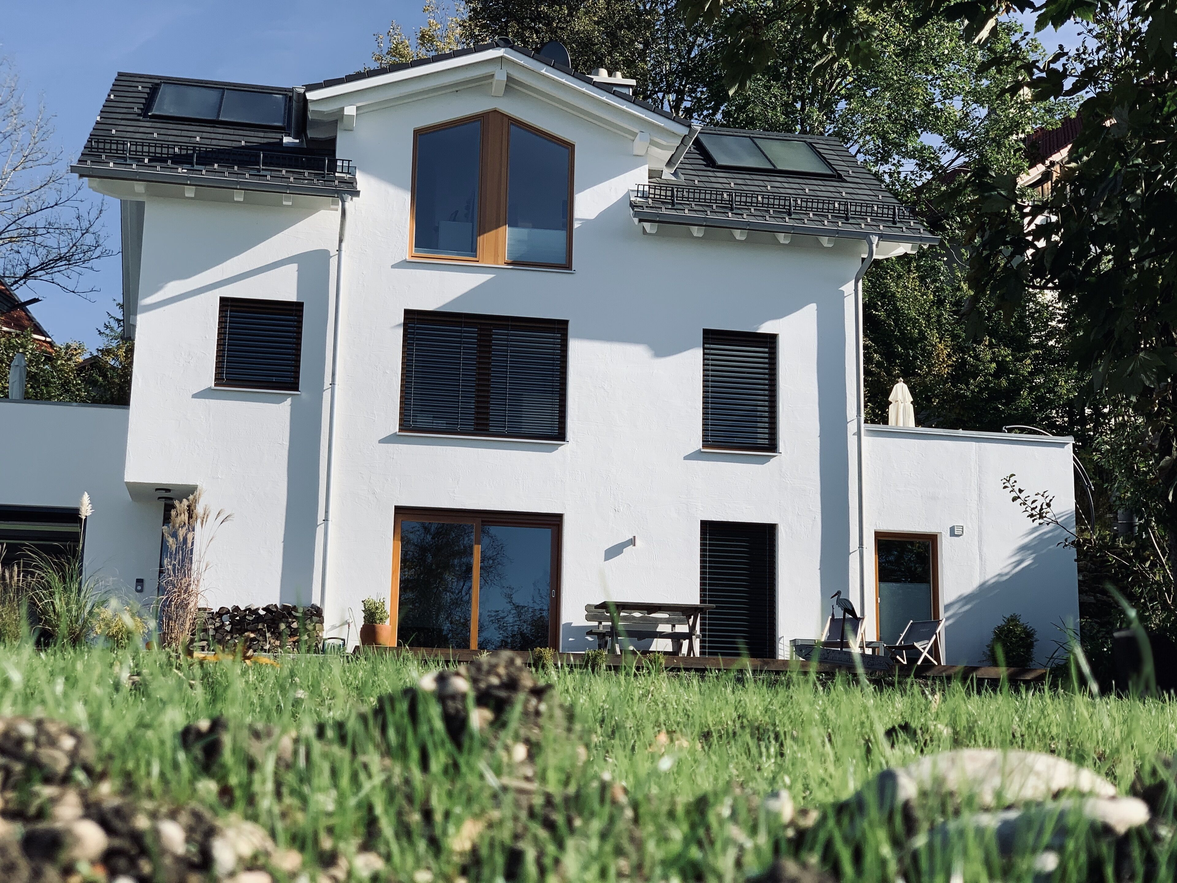 Ein zweistöckiges Haus mit flachem Dach, großen Fenstern und einer Terrassenfläche.