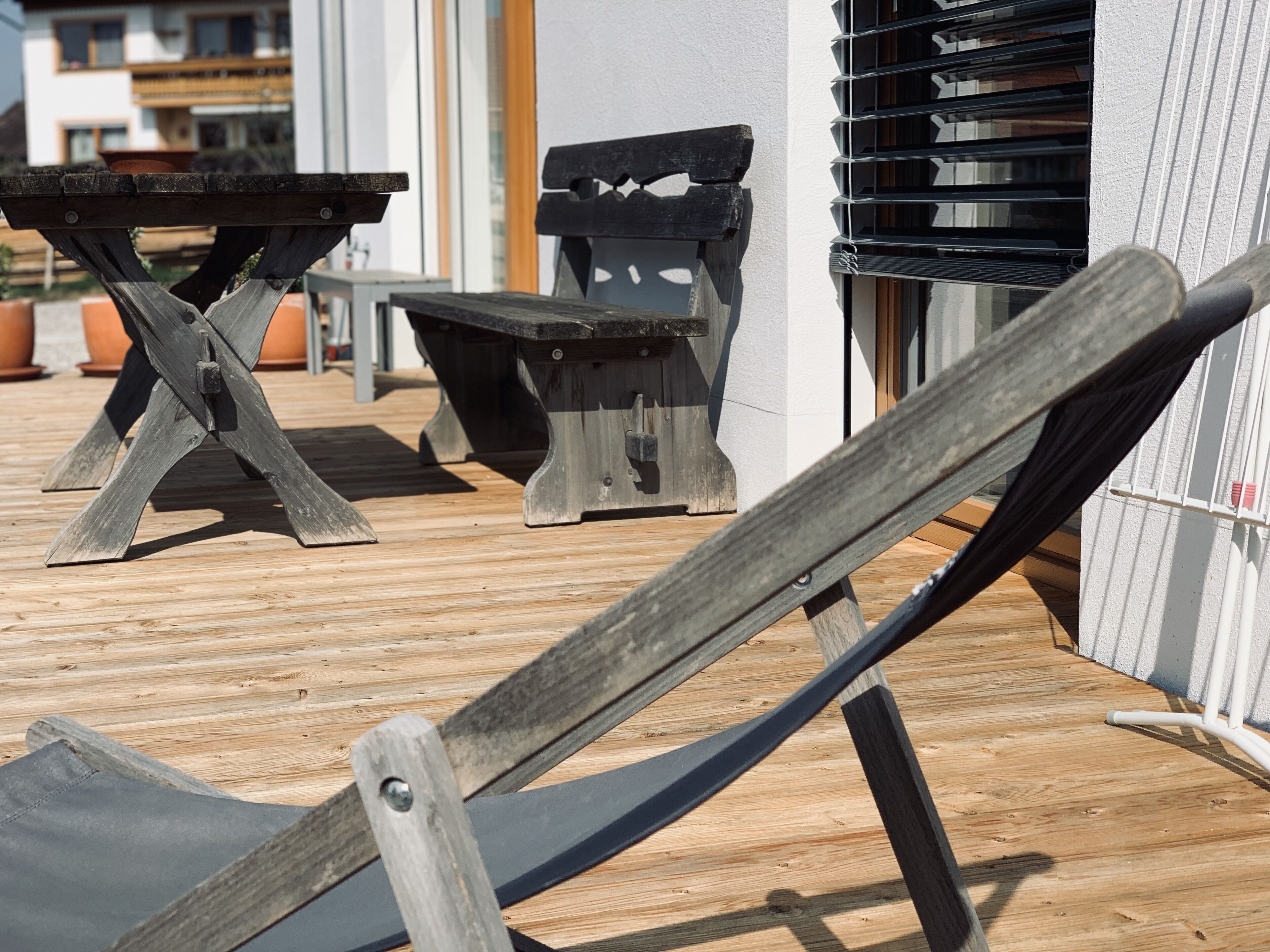 A wooden deck with a hammock, a wooden table, and a bench.