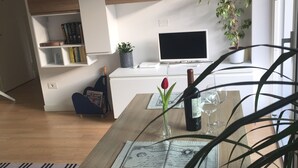 Moderni olohuone, jossa on puinen ruokapöytä, televisio ja kirjahylly.