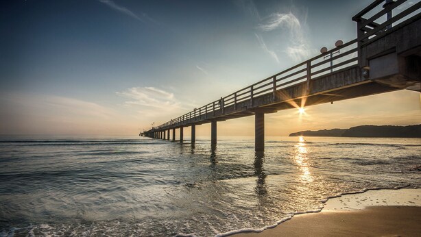 A pier extending into calm waters at sunset.