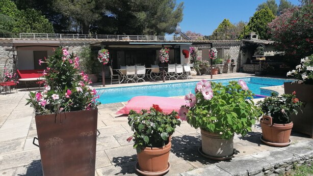 A pool area with a stone deck, outdoor seating, and potted plants.