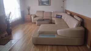 Ein modernes Wohnzimmer mit einem beigefarbenen Ecksofa, einem kleinen Couchtisch und einem Gemälde an der Wand.