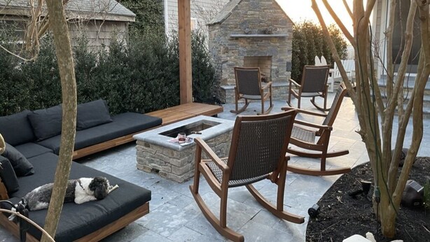 Un patio al aire libre con chimenea de piedra, zona de estar y una pérgola.