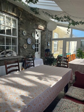 Interior rústico de piedra con una mesa de comedor, sillas y vistas a través de una ventana.