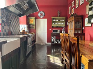 Una cocina con pared roja, un reloj y una mesa de comedor de madera.