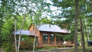 Une cabane dotée d’une terrasse en bois, entourée d’arbres.