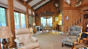 L’intérieur chaleureux d’un chalet en bois comprend un coin repas, des fauteuils en cuir et un escalier.