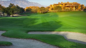 Un campo de golf con búnkeres y un edificio de varios pisos al fondo.